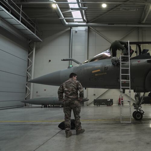 A flight-crew member climbs into the cockpit of a French air force Rafale fighter jet stationed on a NATO air-policing mission at the Siauliai Air Base in Lithuania as another member of the French detachment stands at the foot of the ladder on Sunday, April 19, 2026 (AP Photo/John Leicester)