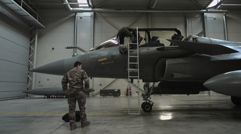 A flight-crew member climbs into the cockpit of a French air force Rafale fighter jet stationed on a NATO air-policing mission at the Siauliai Air Base in Lithuania as another member of the French detachment stands at the foot of the ladder on Sunday, April 19, 2026 (AP Photo/John Leicester)