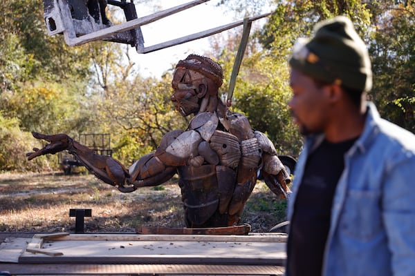 Jonathan Imafidor stands in front of his sculpture that was burned in a fire that occurred at South River Arts Studio. “The creativity is still there. I’ll be able to bounce back and create stuff. It’s just a temporary setback,” Imafidor says. (Natrice Miller/AJC)