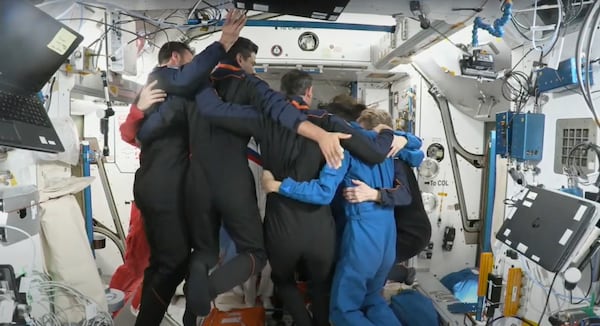 This photo provided by Axiom Space shows the 11 astronauts aboard the International Space Station on Sunday July 13, 2025 sharing a group hug ahead of Monday's planned departure of the private crew of four. (Axiom Space via AP)