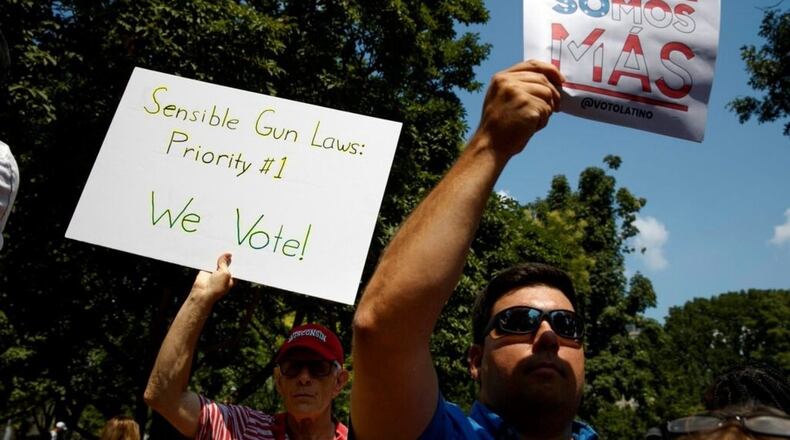 Men hold up signs during a rally against racism and white nationalism and in favor of gun laws, Tuesday, Aug. 6, 2019, near the White House in Washington.