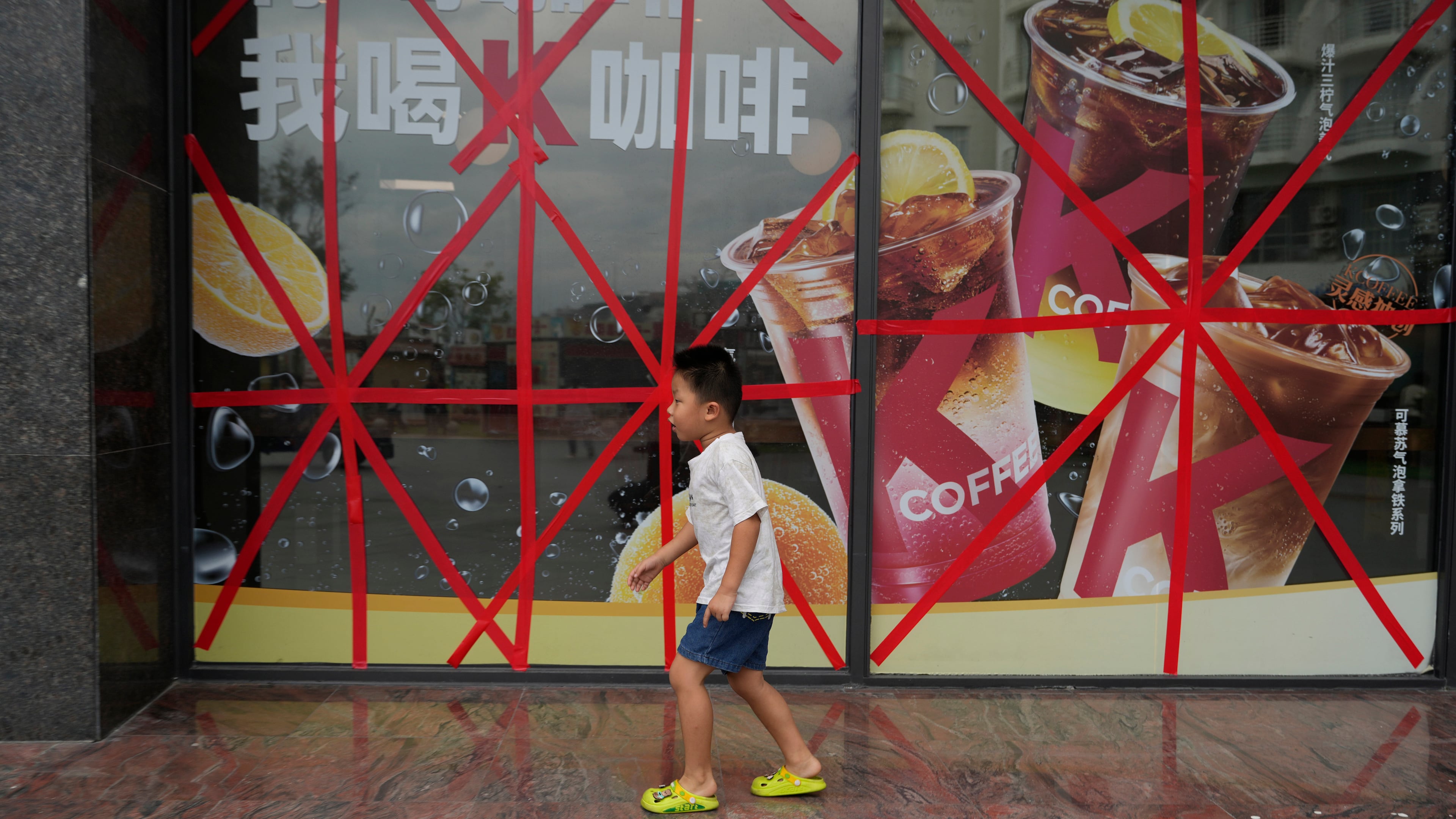 A child passes by a restaurant with its glass windows taped protectively against strong winds ahead of Super Typhoon Ragasa in Shenzhen in southern China's Guangdong province on Tuesday, Sept. 23, 2025. (AP Photo/Ng Han Guan)