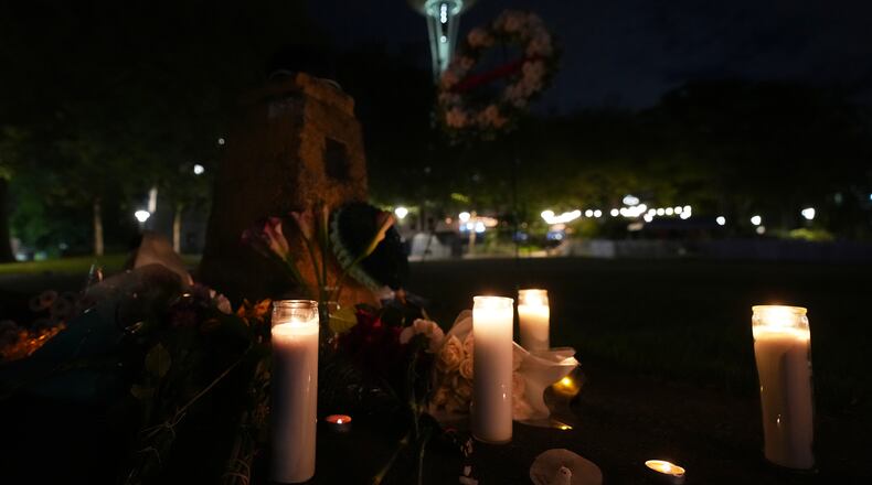 Flowers and candles are seen placed with the Space Needle at background, during the vigil for victims the day after a shooting at Seattle Center during the Bite of Seattle food festival, Monday, July 27, 2026, in Seattle. (AP Photo/Lindsey Wasson)