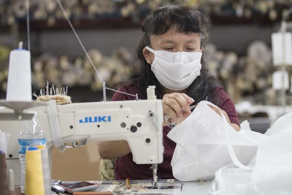Angelica Caballero clips excess string from an isolation medical gown she’s sewing together at Echota Fabrics, Inc. in Calhoun on April 8, 2020. Echota normally produces fabrics for curtains and bedding but is participating in an informal regional consortium making medical gowns and fabric face masks for health-care workers responding to the COVID19 pandemic. (ALYSSA POINTER / ALYSSA.POINTER@AJC.COM)