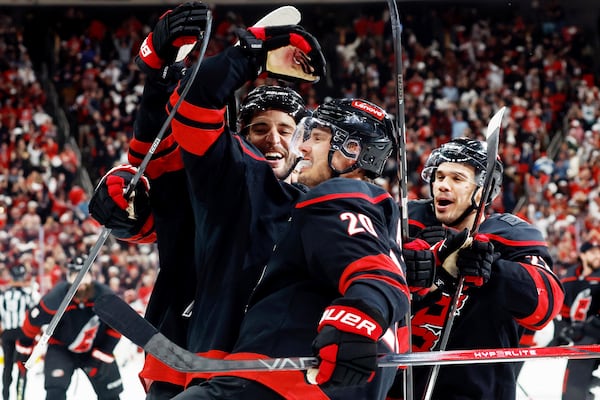 Carolina Hurricanes' Sebastian Aho, center, celebrates with teammates Shayne Gostisbehere, left, and Logan Stankoven (22) Aho's game winning overtime goal during the second overtime period of Game 5 of an NHL hockey Stanley Cup first-round playoff series against the New Jersey Devils in Raleigh, N.C., Tuesday, April 29, 2025. (AP Photo/Karl DeBlaker)