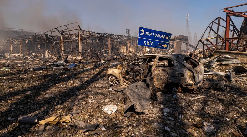 A view of a destroyed car amid damaged buildings, with a road sign showing the direction and distance to Kyiv and Zhytomyr after a Russian attack struck a warehouse, followed by an explosion, in the village of Myla, Kyiv region, Ukraine, Saturday, Aug. 29, 2026. (AP Photo/Dan Bashakov)