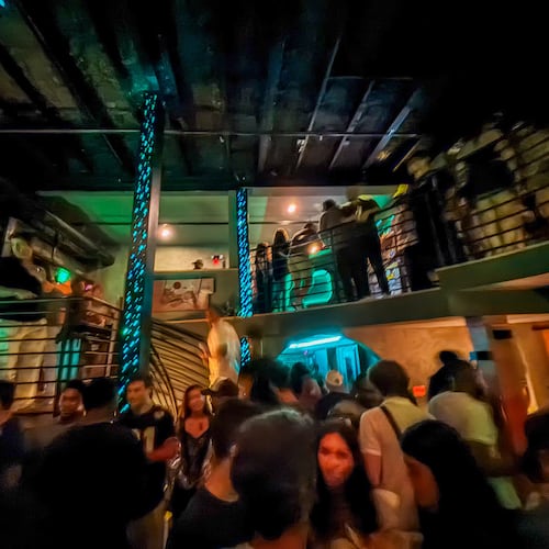A multi-level bar at night filled with people.