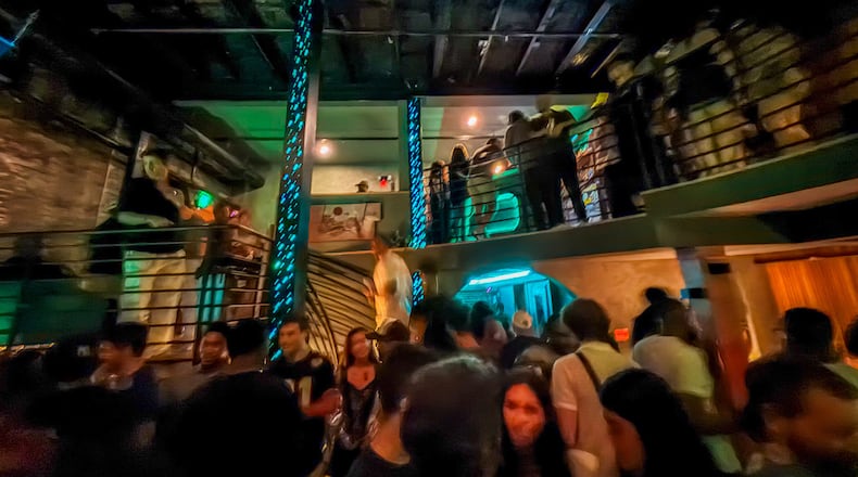 A multi-level bar at night filled with people.
