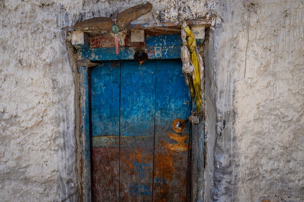 A prayer flag and lock are placed on an abandoned door of a house in the village of Samjung, in the Mustang region, 462 kilometers (288 miles) west of Kathmandu, Nepal, Friday, April 18, 2025. (AP Photo/Niranjan Shrestha)
