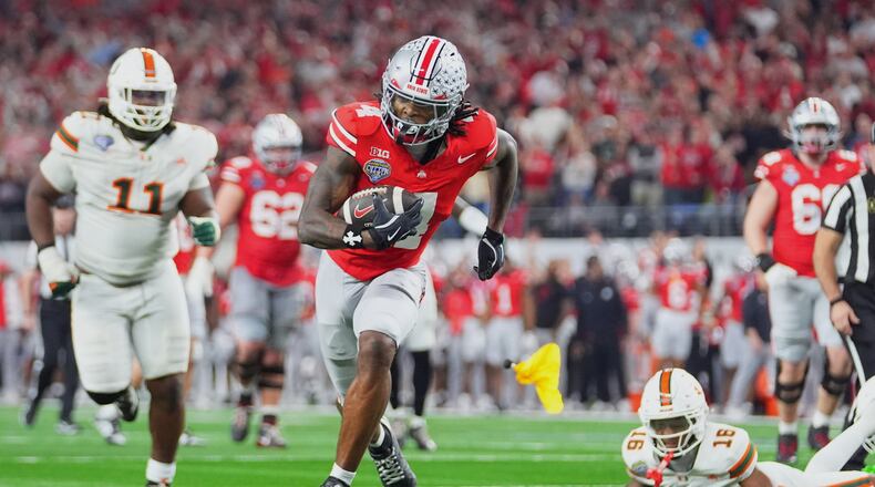 FILE - Ohio State wide receiver Jeremiah Smith, center, gets away from Miami defensive lineman David Blay Jr. (11) and defensive back Ja'Boree Antoine (16) to score a touchdown during the second half of the Cotton Bowl College Football Playoff quarterfinal game Wednesday, Dec. 31, 2025, in Arlington, Texas. (AP Photo/Julio Cortez, File)