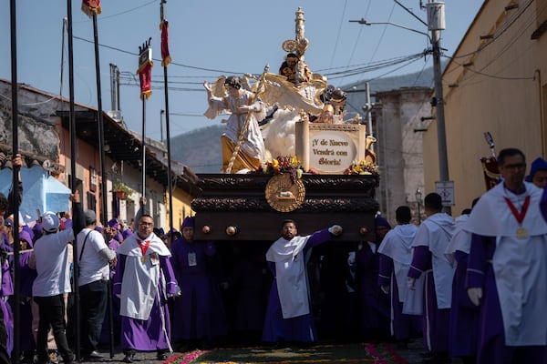 Faithful carry a platform with a statue of Jesus of Nazareth, wearing a tunic created by weavers at the Maria Auxiliadora embroidery workshop, during a Lenten season procession in Antigua, Guatemala, Sunday, April 6, 2025. (AP Photo/Santiago Billy)