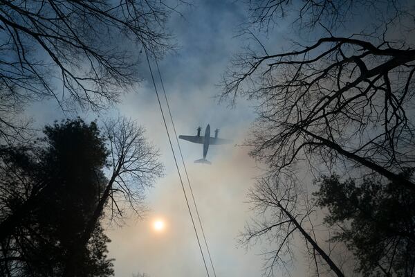 A helicopter does a water drop on the Black Cove Fire Wednesday, March 26, 2025, in Saluda, N.C.. (AP Photo/Allison Joyce)