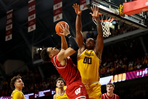 Wisconsin guard John Tonje, center left, shoots while Minnesota forward Frank Mitchell (00) jumps to block during the second half of an NCAA college basketball game, Wednesday, March 5, 2025, in Minneapolis. (AP Photo/Ellen Schmidt)