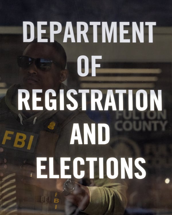 An FBI agent can be seen behind the doors of the Fulton County Election Hub and Operation Center in Union City on Wednesday, Jan. 28, 2026. (Arvin Temkar/AJC)