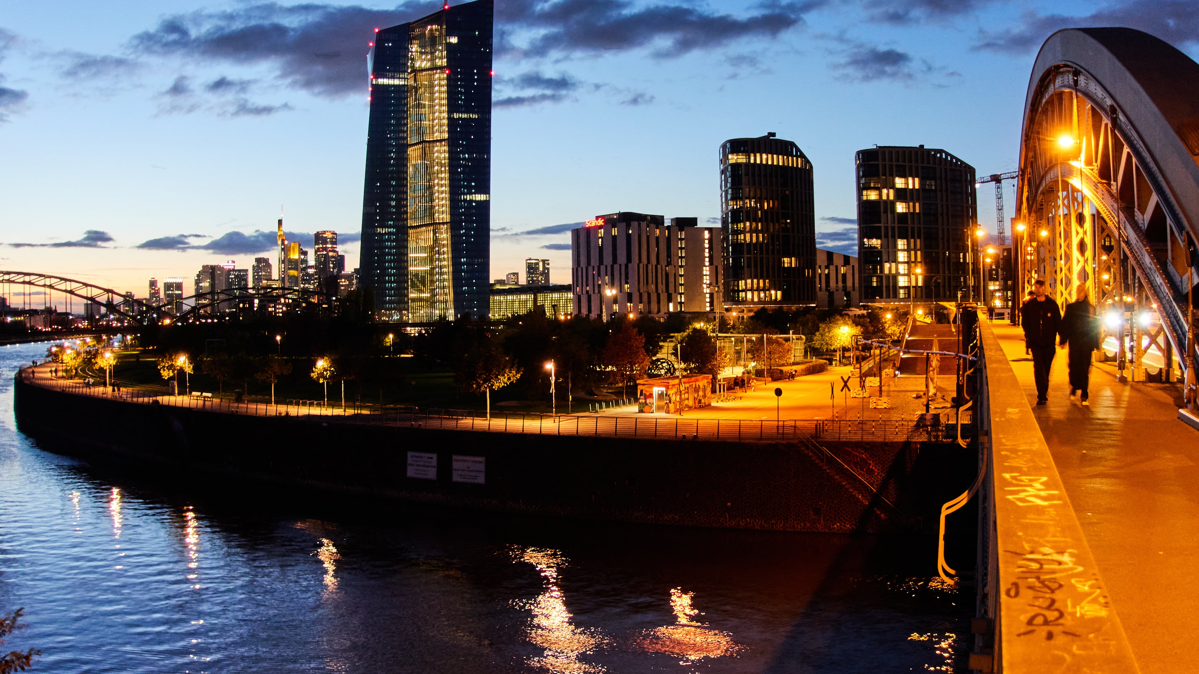 People walk over a bridge near the European Central Bank in Frankfurt, Germany, Sunday, Oct. 26, 2025. (AP Photo/Michael Probst)