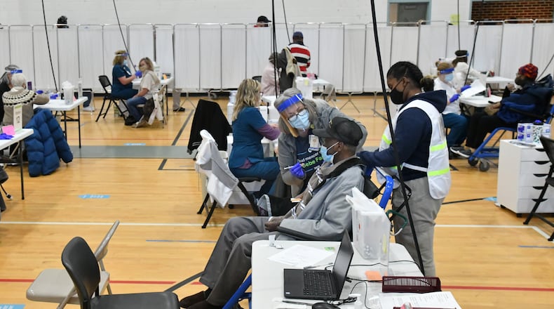 Registered Nurse Kathy Martin, center, prepares to administer a COVID-19 vaccine to Arthur Smith at Phoebe Healthworks building in Albany on Wednesday. Caregivers at nursing homes and other long-term care facilities have faced the reality of the COVID-19 pandemic like few have across Georgia. (Hyosub Shin / Hyosub.Shin@ajc.com)