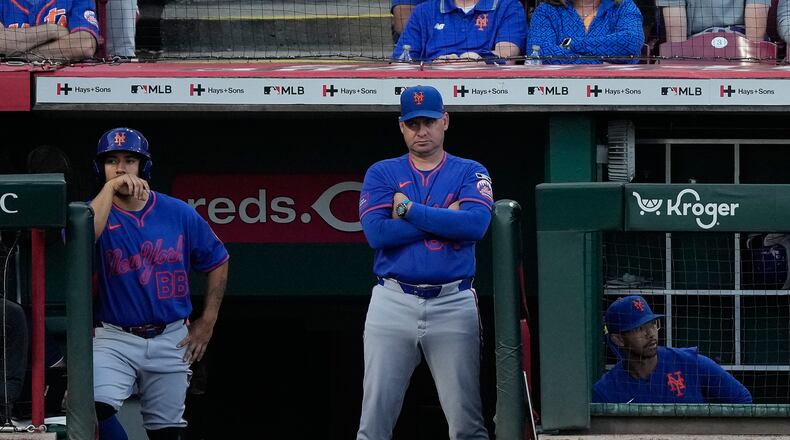 New York Mets manager Carlos Mendoza center, looks out from the dugout during the fourth inning of a baseball game against the Cincinnati Reds in Cincinnati, Monday, June 15, 2026. (AP Photo/Carolyn Kaster)