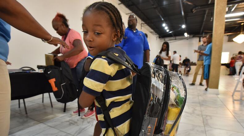 A child poses with a clear backpack at a school supply distribution event. Starting next school year, Rockdale County Public Schools will require all students to use clear backpacks as a safety measure in its buildings. HYOSUB SHIN / HSHIN@AJC.COM