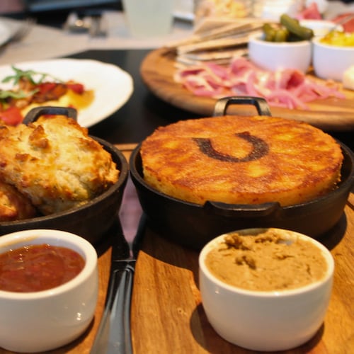 A full table featuring biscuits and cornbread on a Lazy Susan with jam and butter in front
