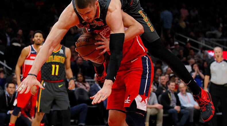 Alex Len (top) of the Hawks is charged with a foul as he falls over Austin Rivers of the Washington Wizards.  (Photo by Kevin C. Cox/Getty Images)