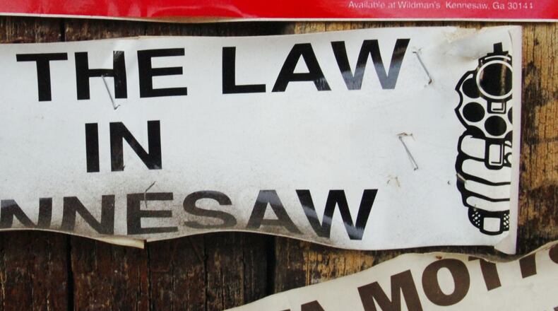 In this 2007 photo, we see a weathered old bumper sticker that refers to the Kennesaw ordinance that requires heads of households to own a firearm – unless they don’t want to. AJC file.