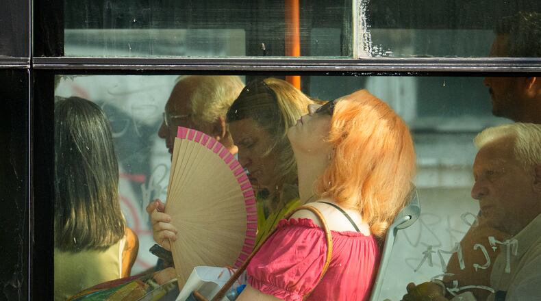 FILE - A woman uses a fan to cool off while riding a bus on a hot day in Bucharest, Romania, Aug. 6, 2026. (AP Photo/Vadim Ghirda)