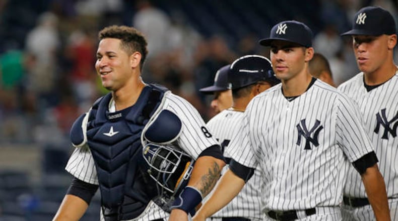 A smiling New York Yankees catcher Gary Sanchez, left, leaves the field with teammates Ben Heller, center, and right fielder Aaron Judge, right, after the Yankees defeated the Baltimore Orioles 14-4 in a baseball game in New York, Friday, Aug. 26, 2016. (AP Photo/Kathy Willens)