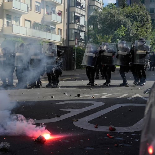 Police form a line in front of a burning flare during a "No G7" demonstration in Geneva, Switzerland, Sunday, June 14, 2026, ahead of the G7 summit scheduled to take place June 15-17. (AP Photo/Baz Ratner)