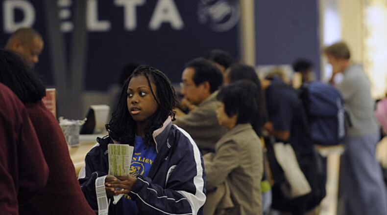Delta passengers check their bags and pick up their tickets at the counter at Hartsfield-Jackson International Airport. Several airlines have added fees for checked luggage.