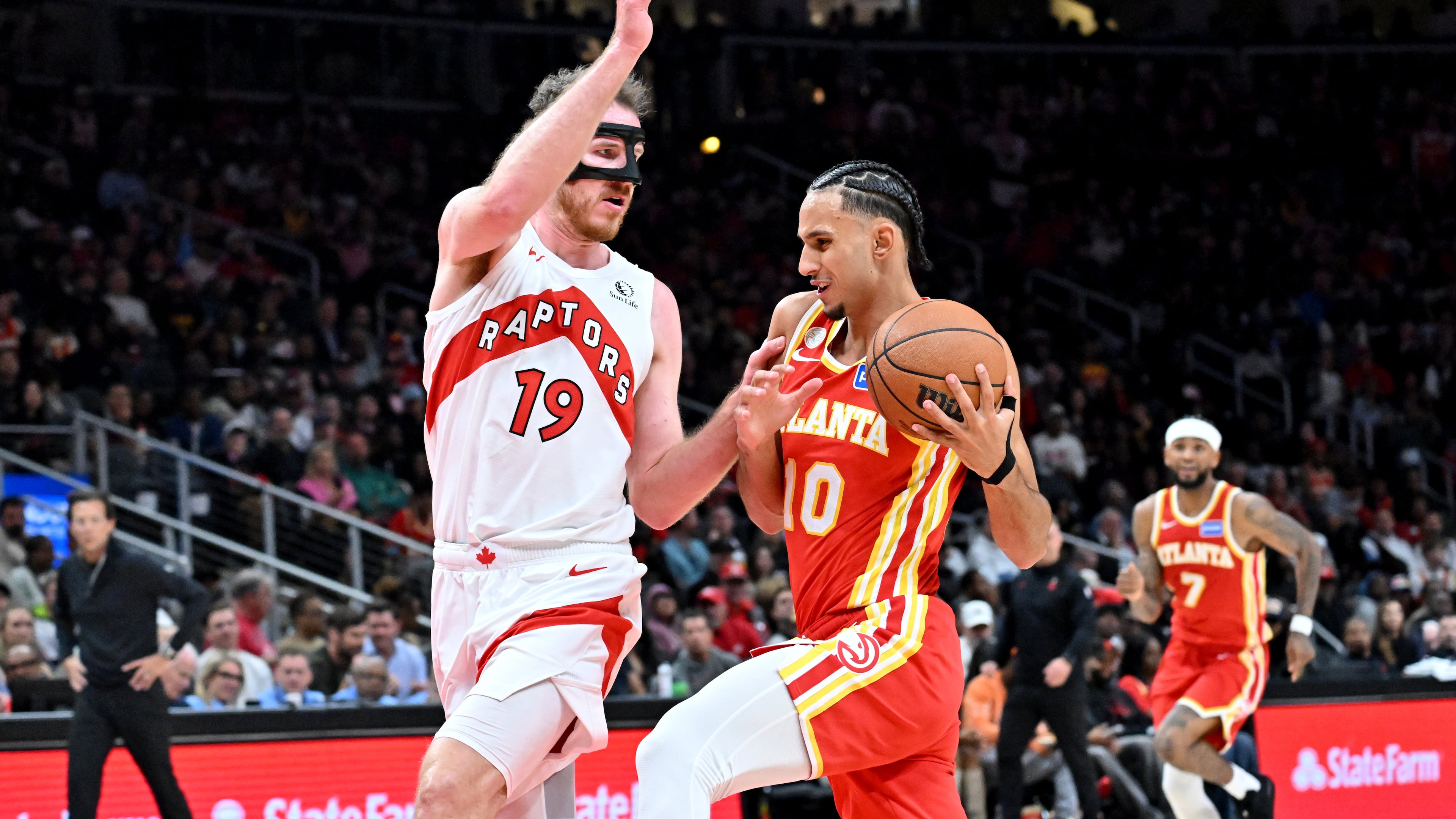 Atlanta Hawks forward Zaccharie Risacher (10) drives against Toronto Raptors center Jakob Poeltl (19) during the second half in the home opener at State Farm Arena, Thursday, October 22, 2025, in Atlanta. Toronto Raptors won 138-118 over Atlanta Hawks. (Hyosub Shin / AJC)