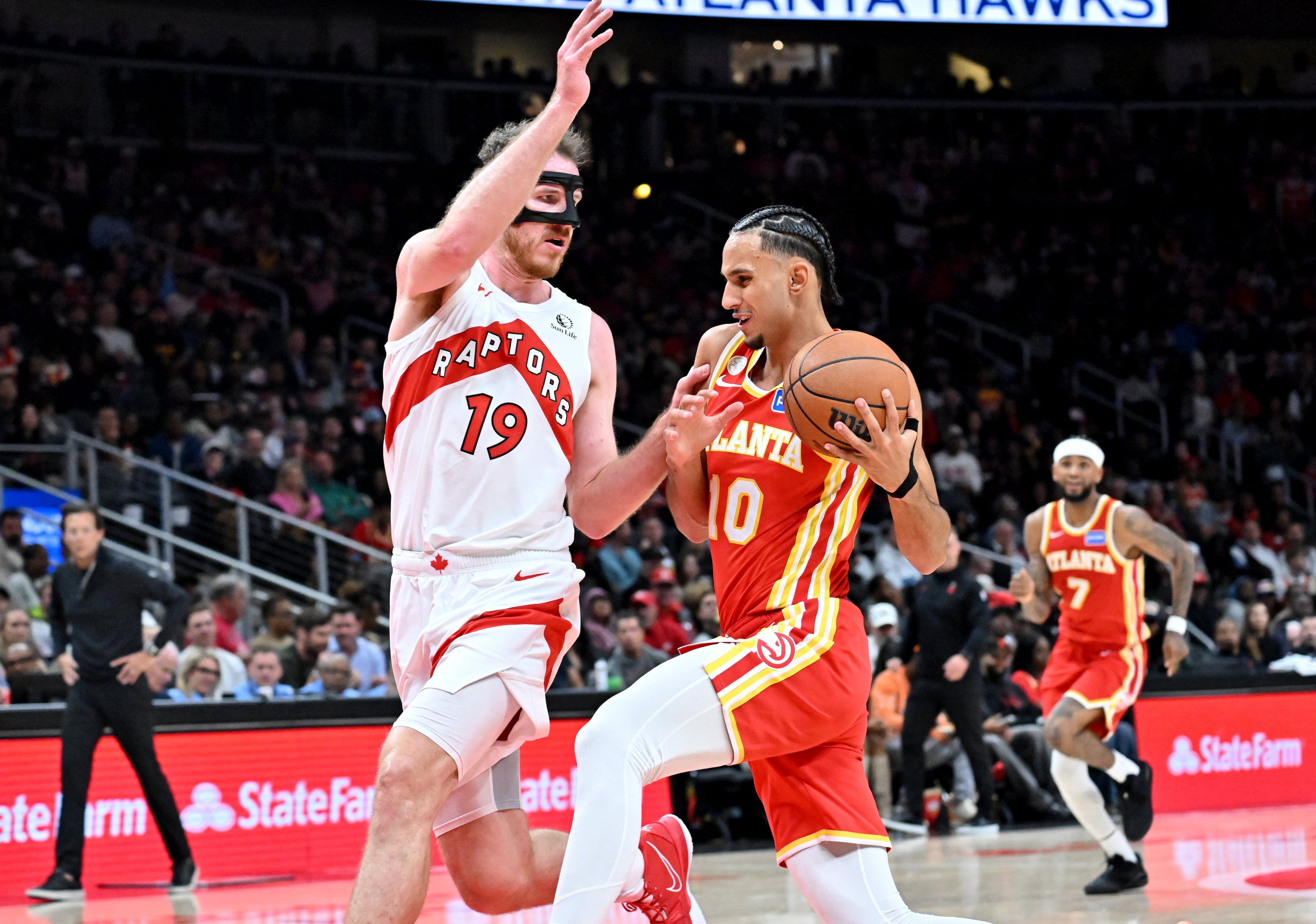 Atlanta Hawks forward Zaccharie Risacher (10) drives against Toronto Raptors center Jakob Poeltl (19) during the second half in the home opener at State Farm Arena, Thursday, October 22, 2025, in Atlanta. Toronto Raptors won 138-118 over Atlanta Hawks. (Hyosub Shin / AJC)