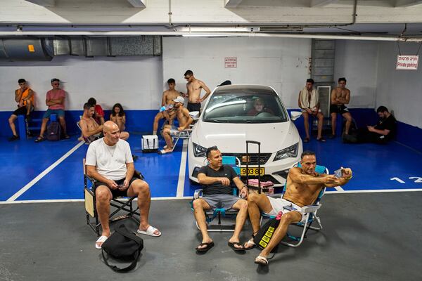 A man takes a selfie while sitting on a beach chair while taking shelter in a parking garage during a missile alert from Iran, in Tel Aviv, Israel, Friday, June 20, 2025. (AP Photo/Bernat Armangue)