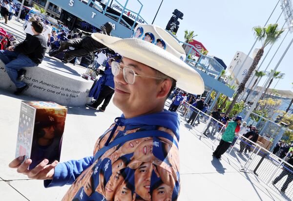 A fan enter Dodger Stadium after receiving a bobblehead doll of Los Angeles Dodgers' Shohei Ohtani before a baseball game against the Atlanta Braves Wednesday, April 2, 2025, in Los Angeles. (AP Photo/Kevork Djansezian)