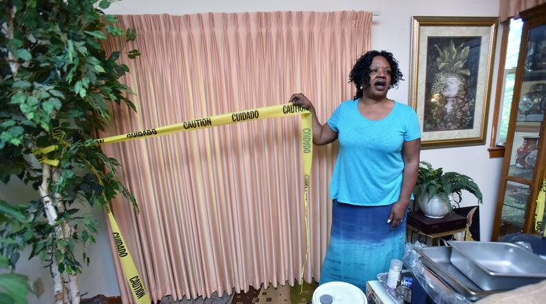 Shelitha Kindell on Thursday shows yellow caution tape she has used near damaged area in her living room caused by explosions to clear land for DeKalb County’s sewage plant construction at her home. Dozens of homes were shaken and damaged by explosions to clear land for DeKalb County’s sewage plant construction, leaving unstable foundations, cracked walls and sunken floors. The county government has agreed to pay more than $500,000 for repairs, but some residents say the money isn’t enough to cover their costs. HYOSUB SHIN / HSHIN@AJC.COM