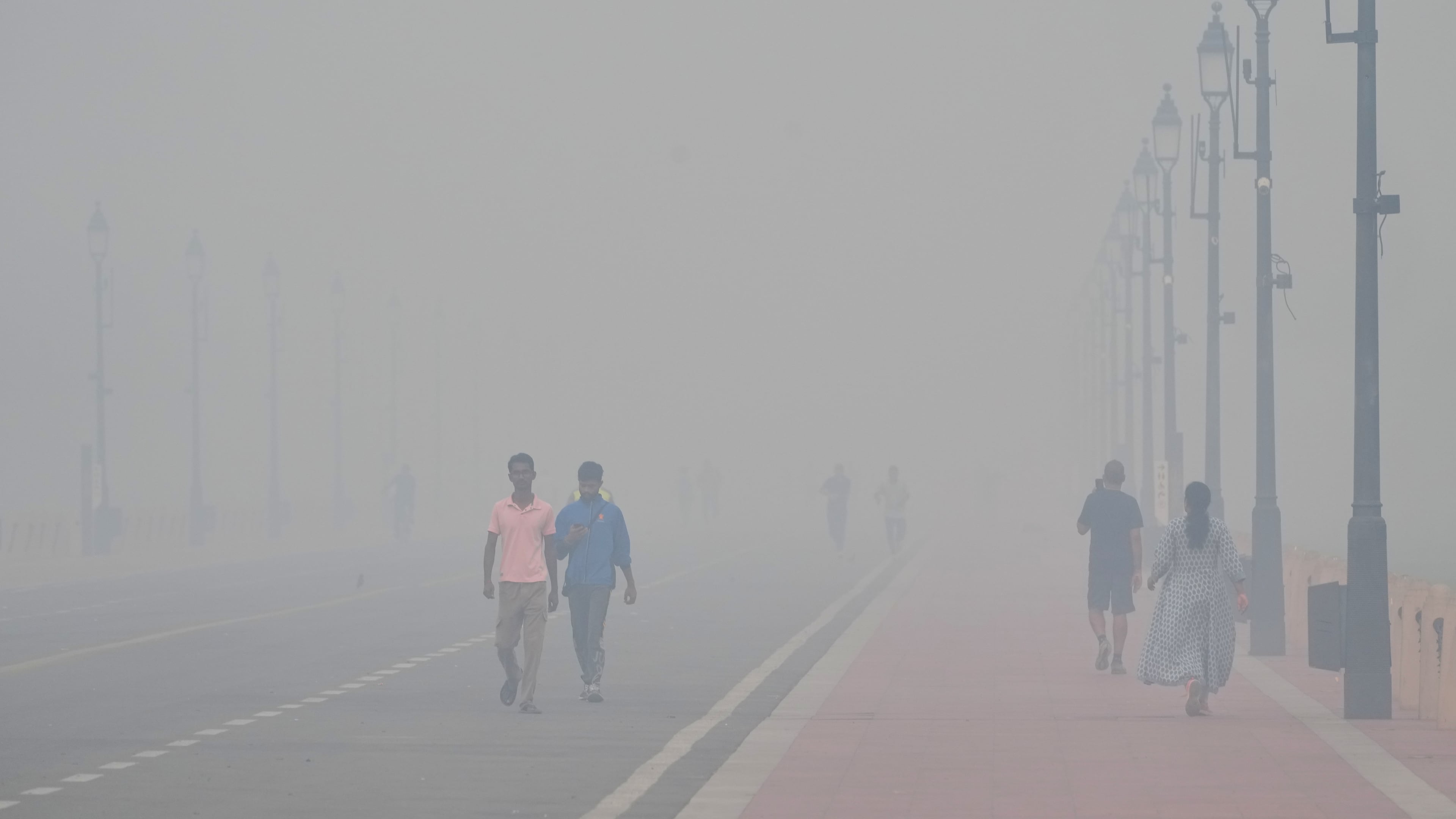 People walk in the morning near the India Gate monument amidst morning smog a day after Diwali festival in New Delhi, India, Tuesday, Oct. 21, 2025. (AP Photo/Manish Swarup)