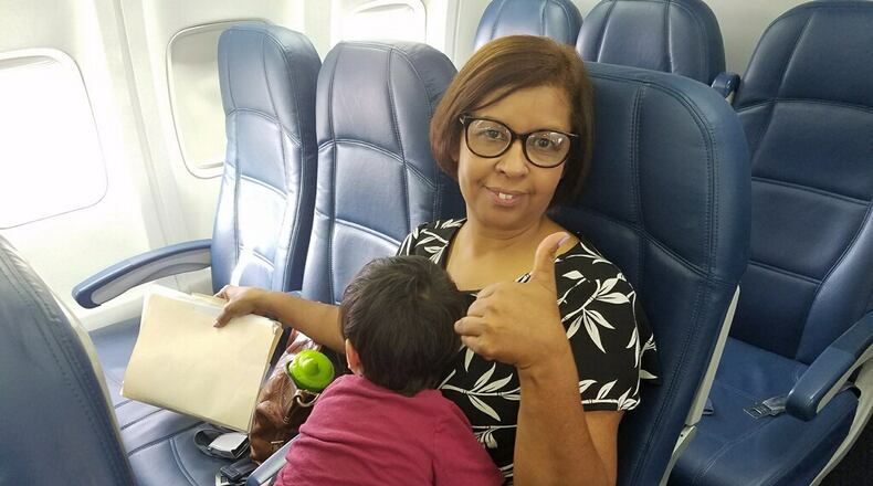 Milagros Cruz, a case manager from the Hall County office of the Georgia Division of Family and Children Services, holds a boy during a flight to Honduras Monday where he and his brothers were reunited with their mother.
