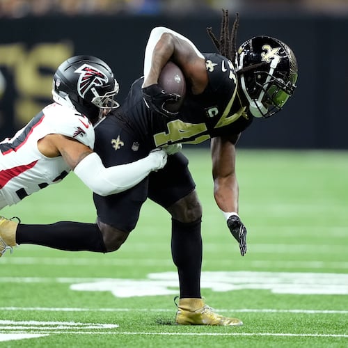 Atlanta Falcons safety Xavier Watts tackles New Orleans Saints running back Alvin Kamara in the first half of an NFL football game, Sunday, Nov. 23, 2025, in New Orleans. (AP Photo/Gerald Herbert)