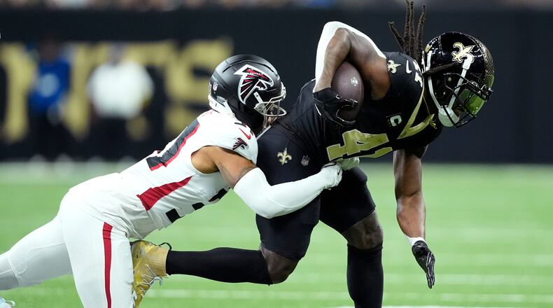 Atlanta Falcons safety Xavier Watts tackles New Orleans Saints running back Alvin Kamara in the first half of an NFL football game, Sunday, Nov. 23, 2025, in New Orleans. (AP Photo/Gerald Herbert)