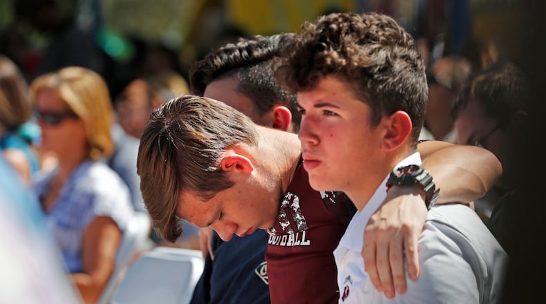 Ryan Schroy, 15, center, bows his head in prayer as he embraces Dylan O'Neill, 15, right, both students at Marjory Stoneman Douglas High School, during a vigil at the Parkland Baptist Church, for the victims of the Wednesday shooting at the high school, in Parkland, Fla., Thursday, Feb. 15, 2018. Nikolas Cruz, a former student, was charged with 17 counts of premeditated murder on Thursday.