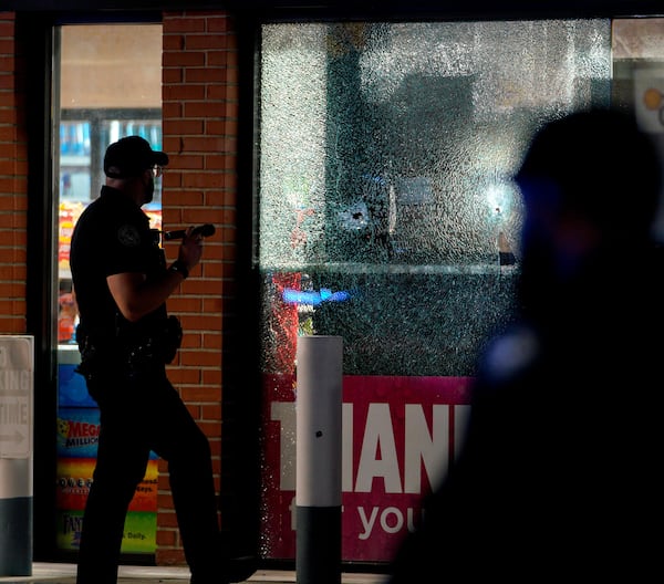 An officer shines his flashlight on a bullet hole in the window a Shell gas station on Northside Drive. Several people were injured in an apparent drive-by shooting.