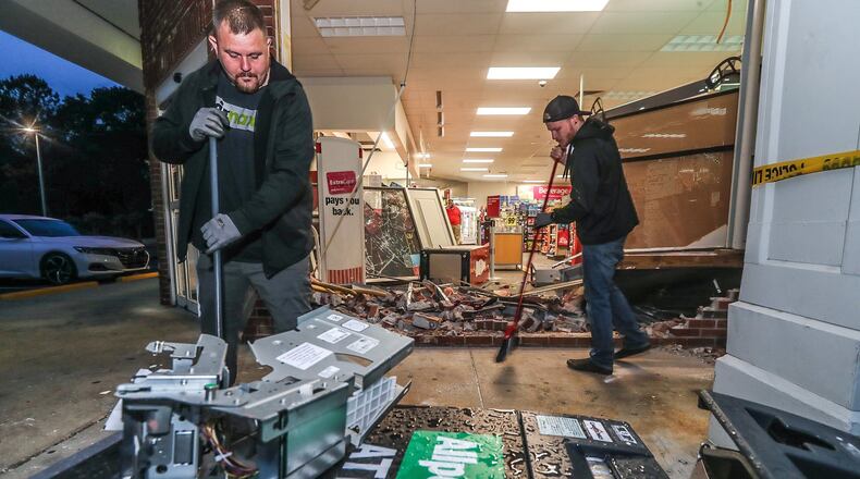 Classic Glass and Door workers Dustin Peterson (left) and Brandon Tallaksen clean up broken glass and debris left after a vehicle plowed into a Mableton CVS.