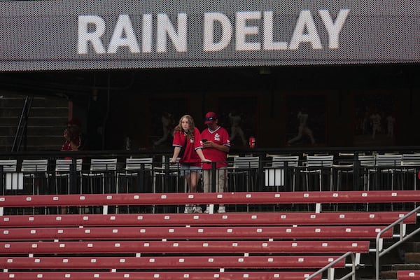 Fans wait out a rain delay during the fifth inning of a baseball game between the St. Louis Cardinals and the Atlanta Braves Sunday, July 13, 2025, in St. Louis. (AP Photo/Jeff Roberson)