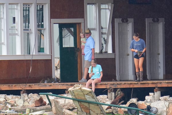 A person salvages a bell from the main building at Camp Mystic along the banks of the Guadalupe River after a flash flood swept through the area Sunday, July 6, 2025, in Hunt, Texas. (AP Photo/Julio Cortez)