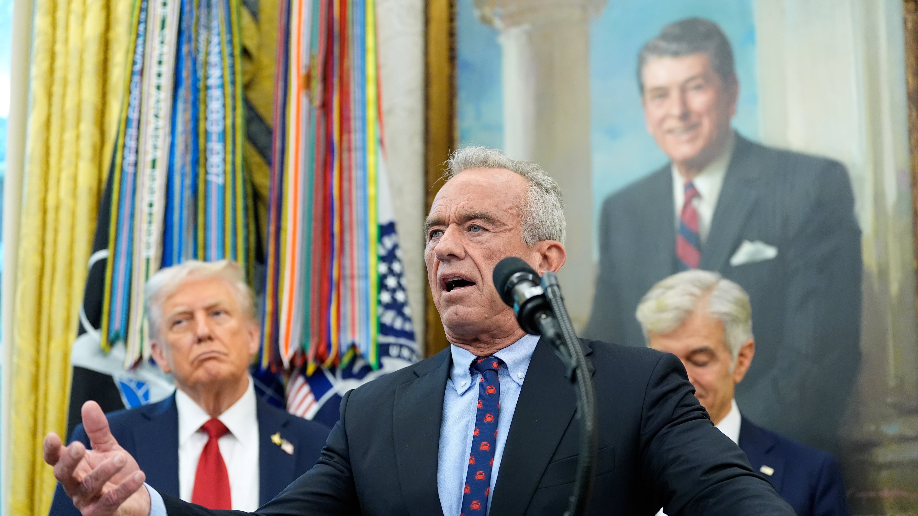 Secretary of Health and Human Services Robert F. Kennedy, Jr., speaks in the Oval Office of the White House, Tuesday, Sept. 30, 2025, in Washington, as President Donald Trump, left, and Mehmet Oz, Administrator for the Centers for Medicare & Medicaid Services, look on. (AP Photo/Alex Brandon)
