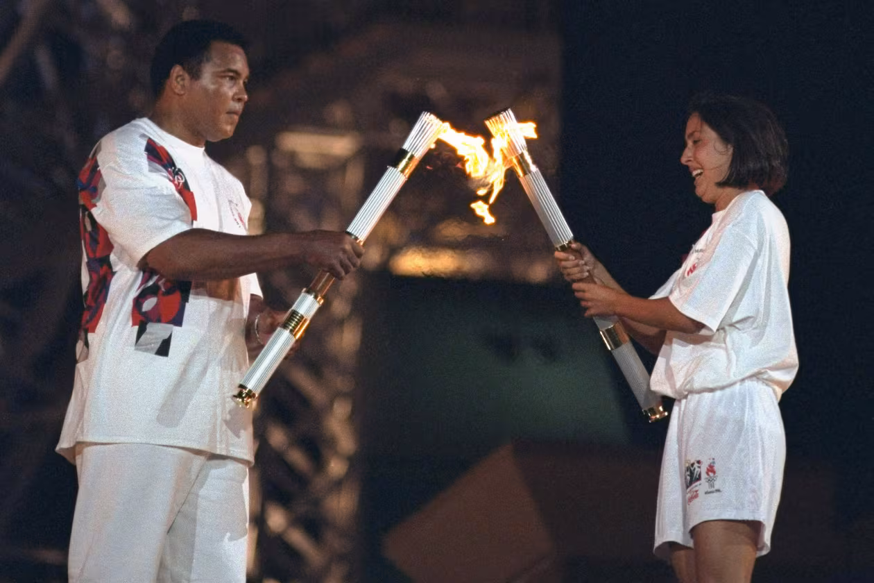 Muhammad Ali and USA swimming athlete Janet Evans carrying torch with flame at Centennial Olympic Stadium. Atlanta, Ga., July 19, 1996. (Courtesy of Lynn Johnson /Sports Illustrated)