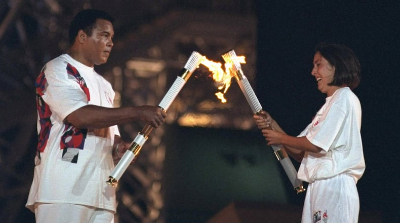 Muhammad Ali and USA swimming athlete Janet Evans carrying torch with flame at Centennial Olympic Stadium. Atlanta, Ga., July 19, 1996. (Courtesy of Lynn Johnson /Sports Illustrated)