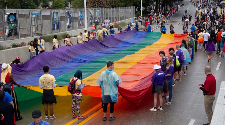 People gather around a giant rainbow flag at the start of the 49th Annual Pride Festival and Parade in Atlanta Sunday, Oct 13, 2019. STEVE SCHAEFER / SPECIAL TO THE AJC