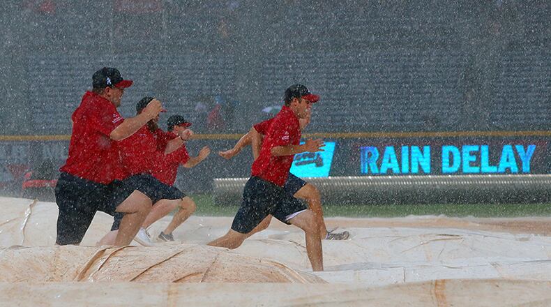 Rain and hail fall on Turner Field while the ground crew scrambles to cover the infield during a rain delay against the Twins in the third inning on Tuesday.