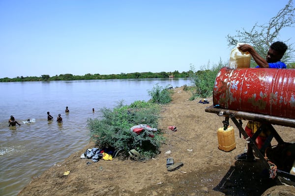 People swim in the Nile River as another fills a water container due to water outages in Khartoum, Sudan, Sunday, May 25, 2025. (AP Photo)