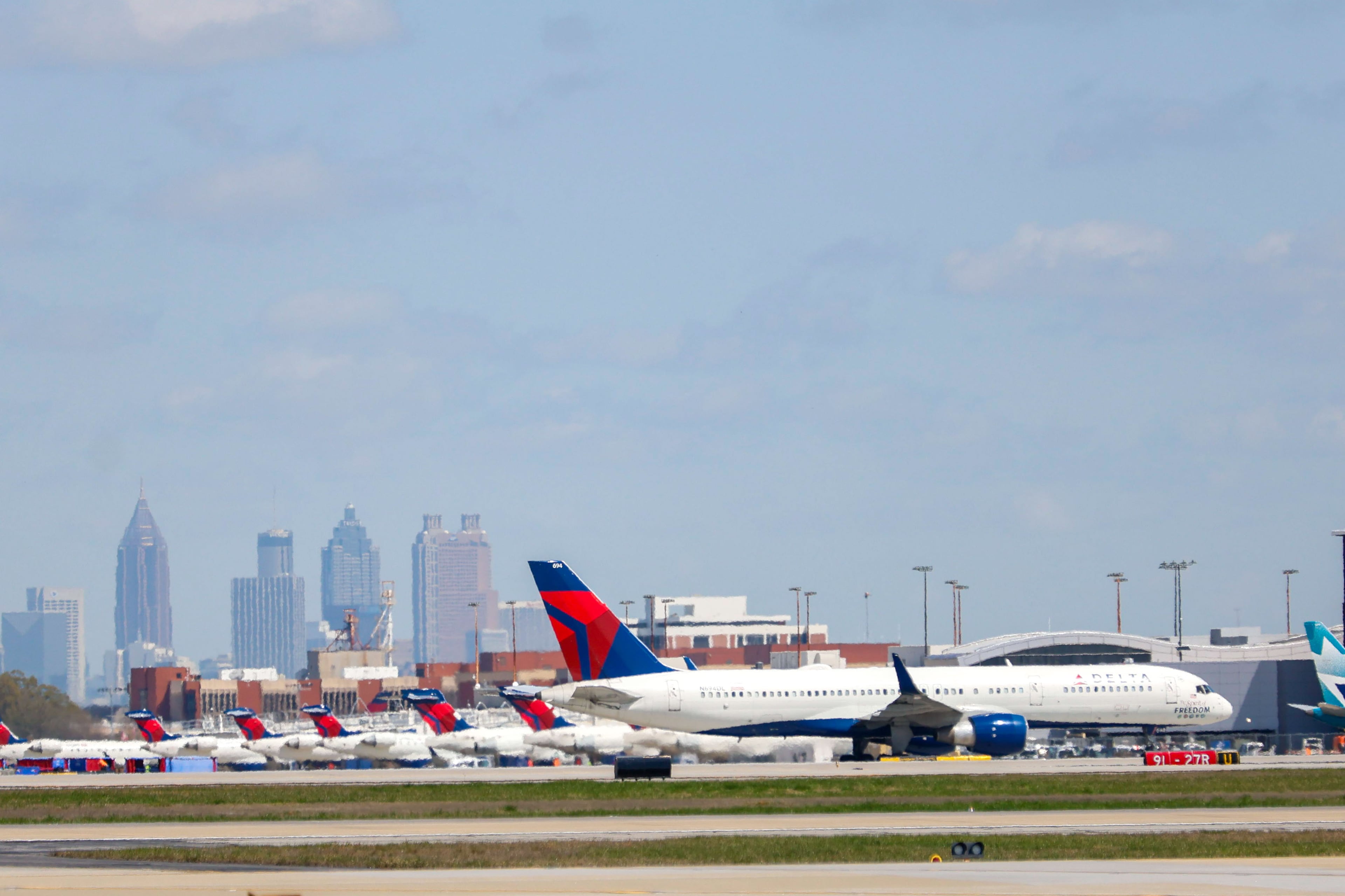 A Delta airplane passes on a taxiway as other Delta planes parked by Concourse D at Hartsfield-Jackson Atlanta International Airport on Wednesday, March 27, 2024. (Miguel Martinez /AJC)